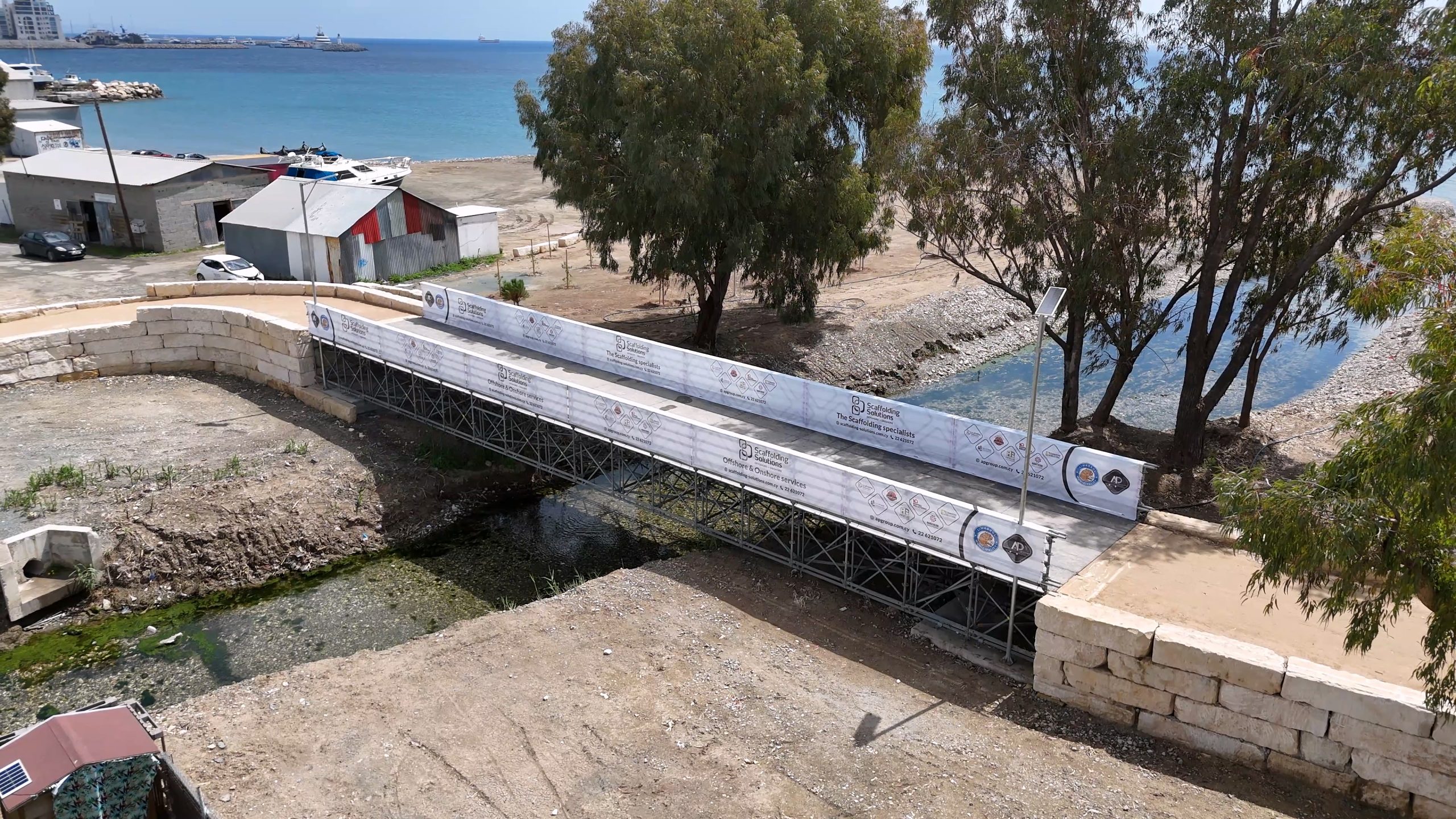 Aerial view of the scaffolding bridge across the Garyllis River in Limassol, with the coast behind it